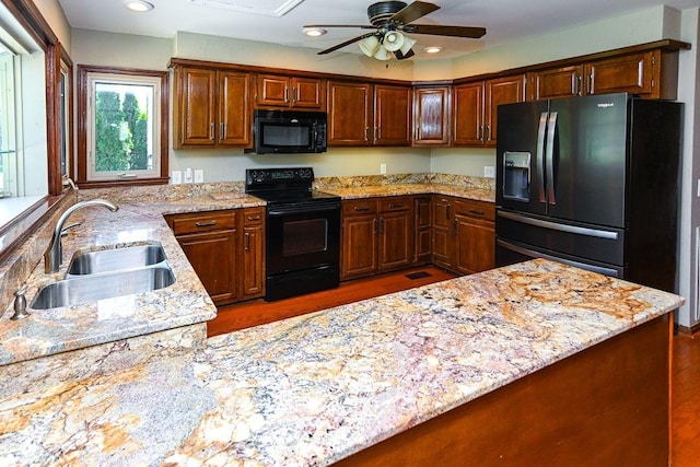 kitchen with light stone countertops, a ceiling fan, black appliances, recessed lighting, and a sink