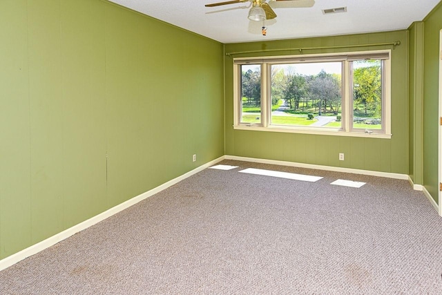 carpeted spare room with visible vents, baseboards, and ceiling fan