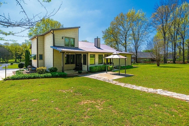 back of property with a patio area, a gazebo, a yard, and a chimney