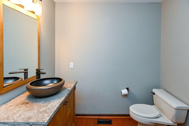 bathroom featuring vanity, baseboards, toilet, visible vents, and wood finished floors