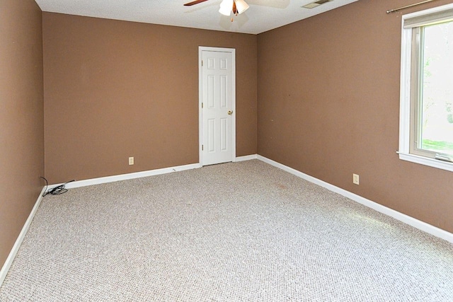 carpeted spare room featuring ceiling fan, a wealth of natural light, and baseboards