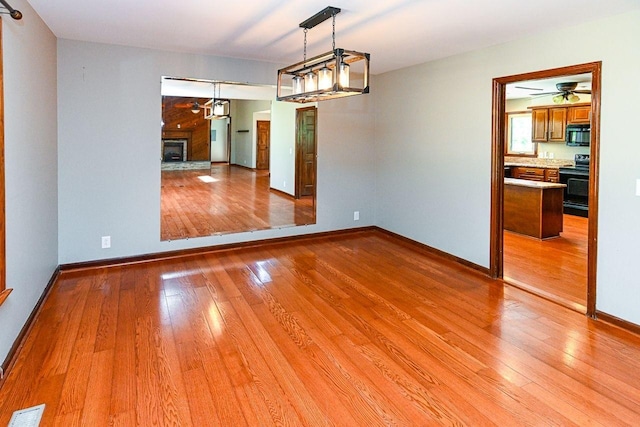 unfurnished room with light wood-style floors, visible vents, baseboards, and a ceiling fan