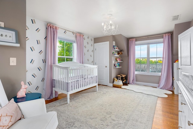 4008 Nevada Ave, Nashville, TN 37209 - bedroom with a notable chandelier, baseboards, a crib, visible vents, and light wood finished floors