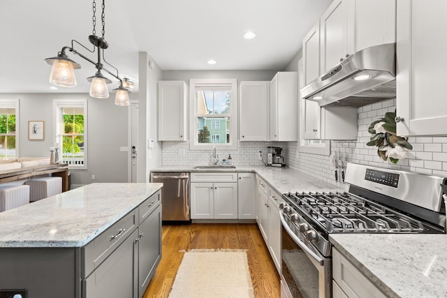 4008 Nevada Ave, Nashville, TN 37209 - kitchen featuring light wood-style floors, under cabinet range hood, appliances with stainless steel finishes, a sink, and decorative backsplash