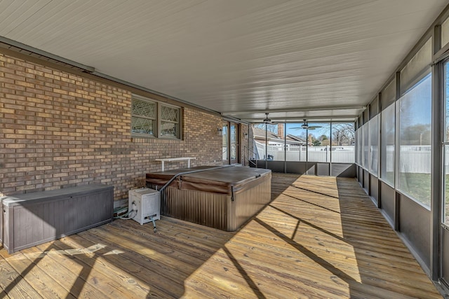 unfurnished sunroom featuring plenty of natural light, a ceiling fan, and a hot tub