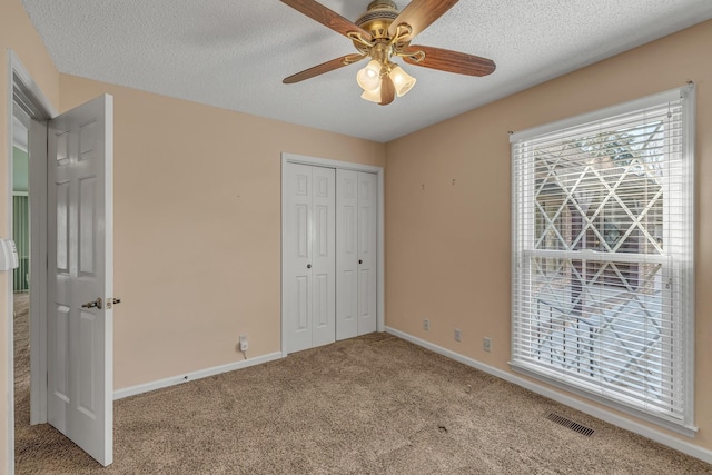unfurnished bedroom with a textured ceiling, a closet, carpet flooring, and visible vents