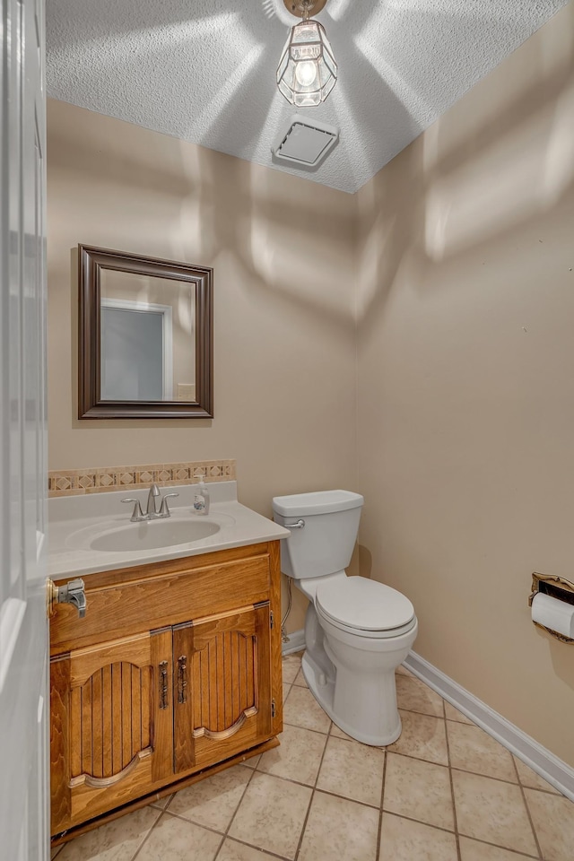 bathroom featuring vanity, baseboards, tile patterned floors, a textured ceiling, and toilet
