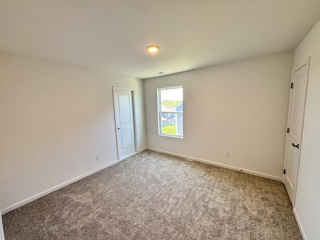 spare room featuring carpet, visible vents, and baseboards