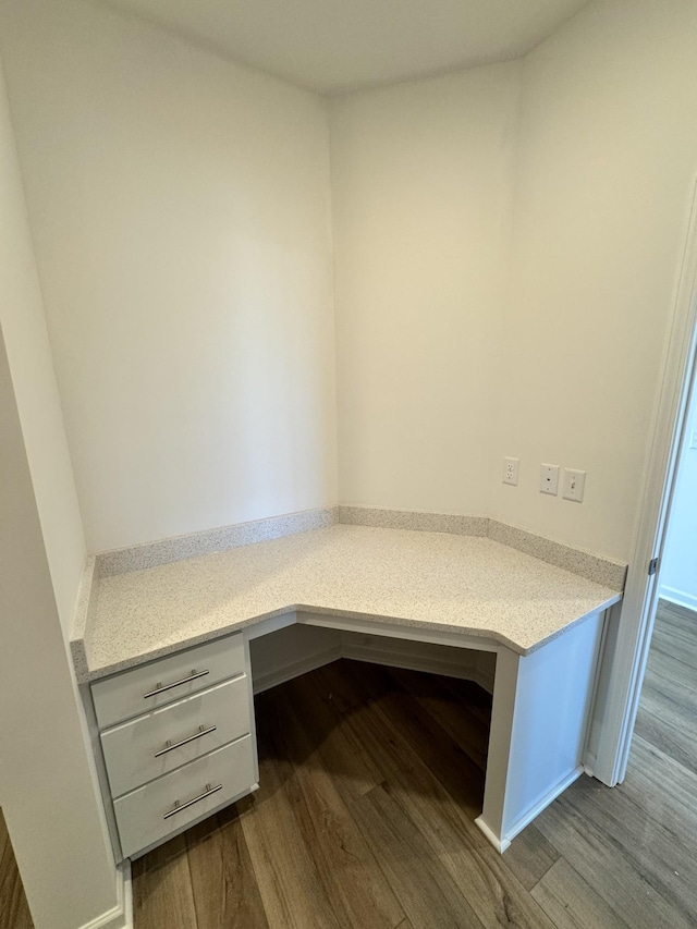 unfurnished office with built in study area and dark wood-type flooring