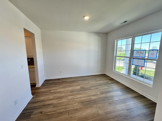 empty room featuring dark wood-type flooring and baseboards