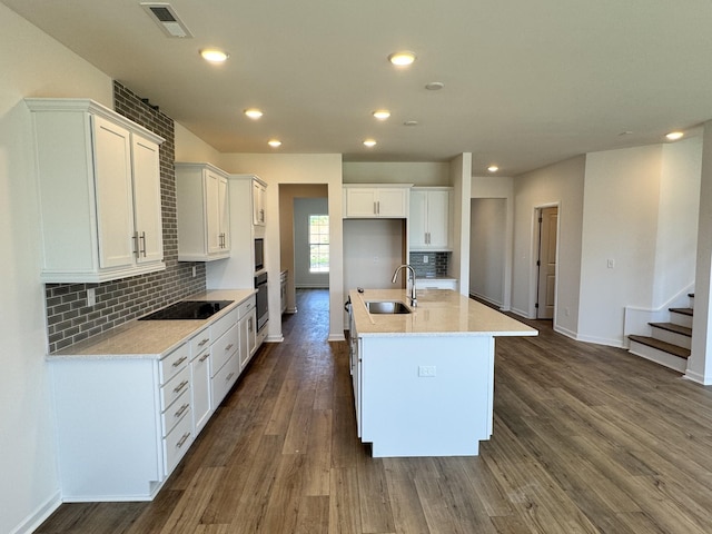 kitchen featuring a sink, baseboards, white cabinetry, and an island with sink