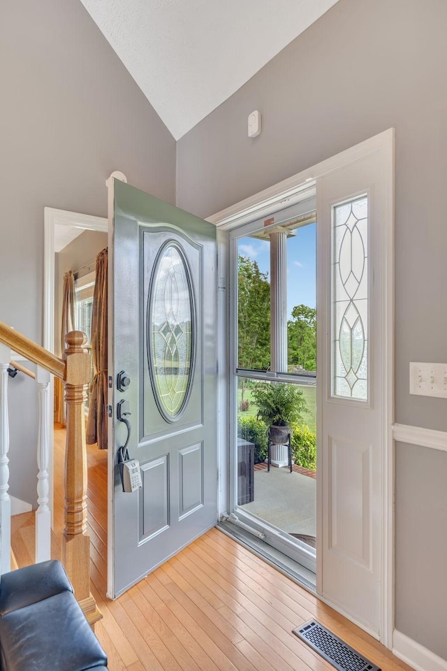 foyer with visible vents, high vaulted ceiling, light wood-style flooring, and stairs