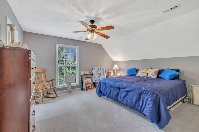 carpeted bedroom featuring a ceiling fan, visible vents, vaulted ceiling, and a textured ceiling