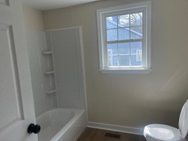 bathroom featuring shower / bathtub combination, visible vents, toilet, wood finished floors, and baseboards