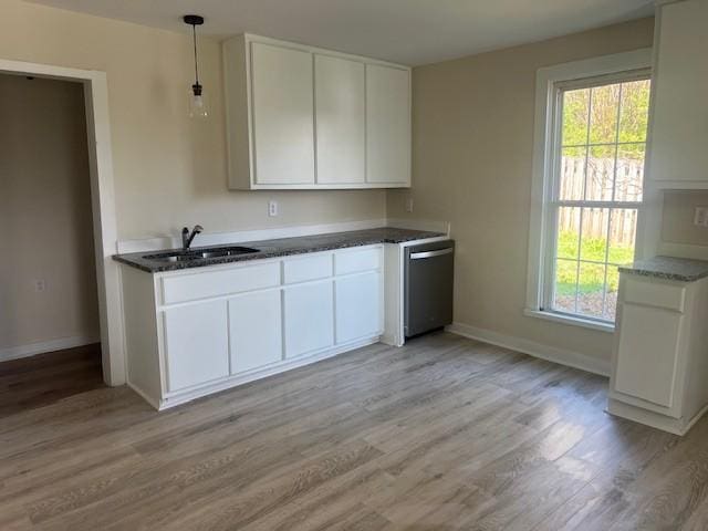 kitchen with light wood-style flooring, dishwasher, a sink, and baseboards