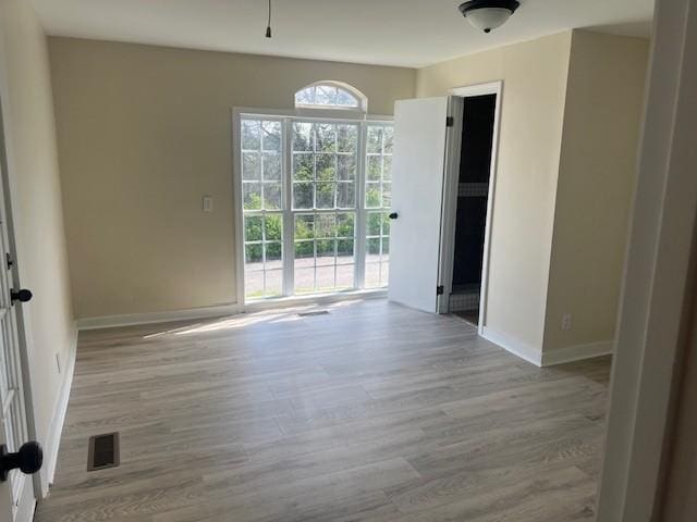 empty room featuring visible vents, baseboards, and wood finished floors