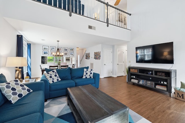 living area with baseboards, wood finished floors, a high ceiling, and visible vents