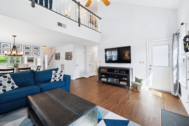 living room with wood finished floors, a high ceiling, a ceiling fan, and visible vents