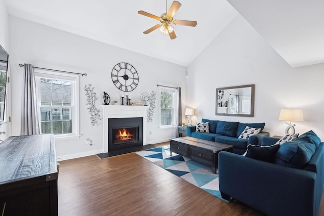 living area featuring high vaulted ceiling, a ceiling fan, wood finished floors, and a fireplace with flush hearth