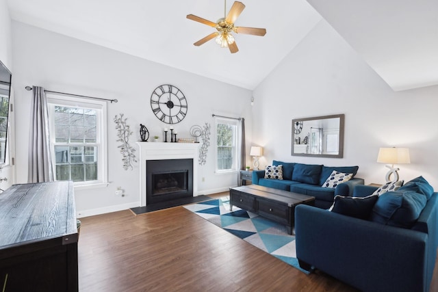 living area with a fireplace with flush hearth, wood finished floors, high vaulted ceiling, and a ceiling fan