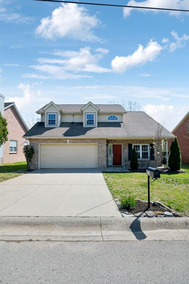 traditional-style home featuring a front yard, a shingled roof, a garage, and driveway
