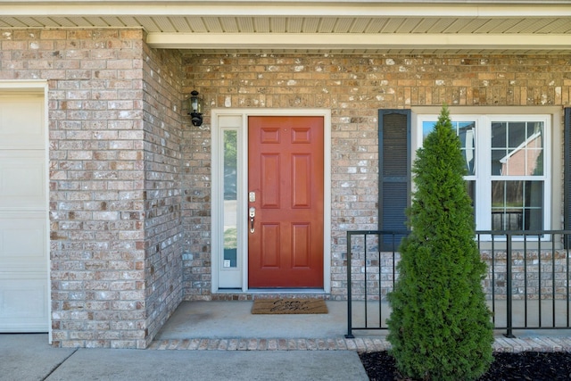 entrance to property with a garage and brick siding