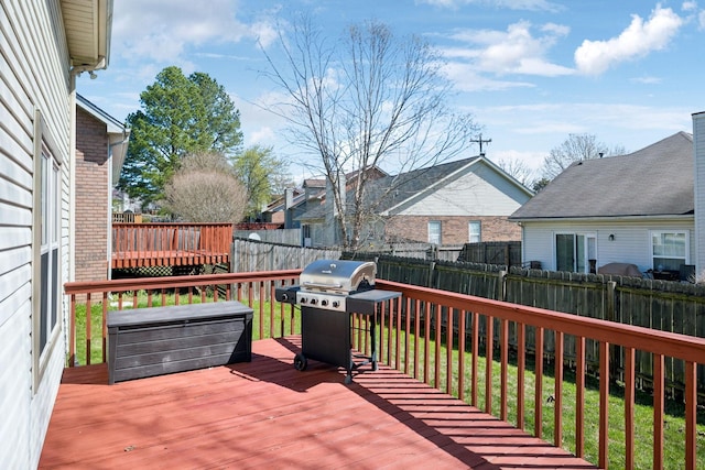 wooden deck featuring fence, a grill, a residential view, and a lawn
