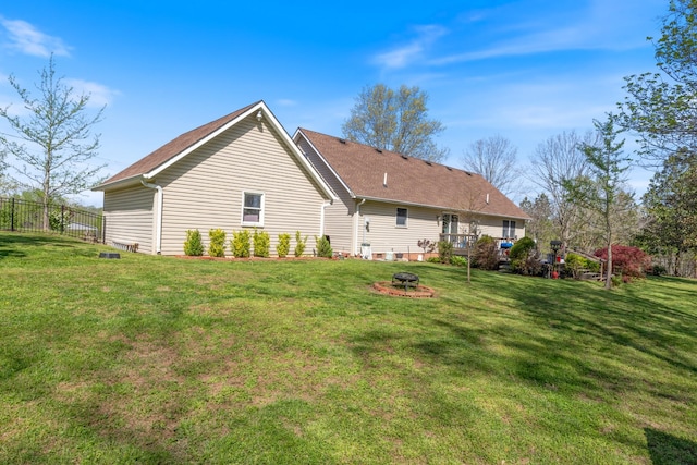 back of house with a fire pit, fence, and a lawn