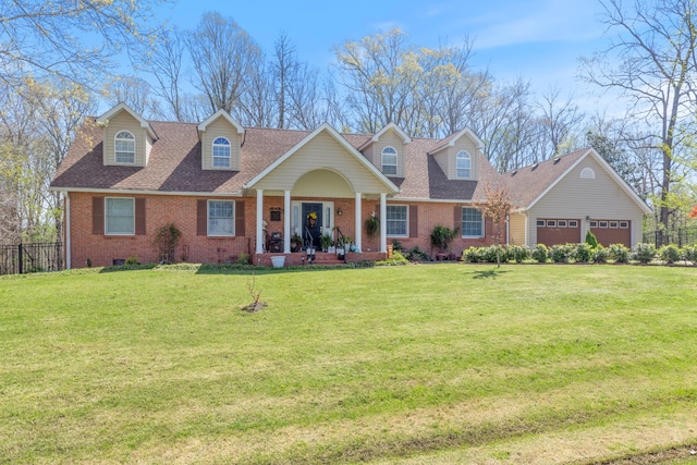 new england style home featuring an attached garage, a front yard, fence, and brick siding