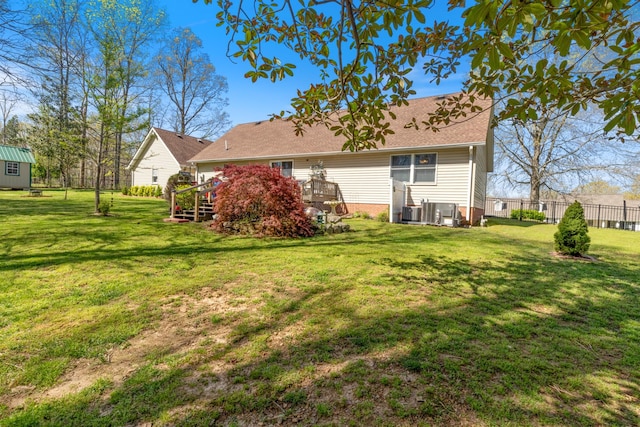 back of house with a shingled roof, a deck, a lawn, fence, and cooling unit