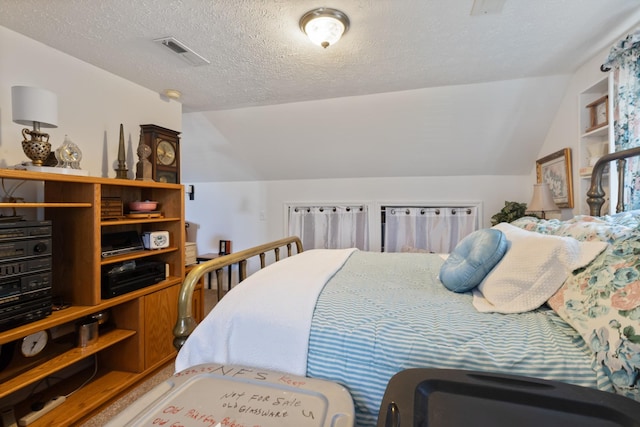 bedroom with a textured ceiling, vaulted ceiling, and visible vents