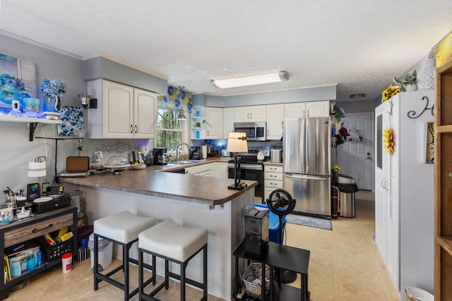 kitchen featuring a peninsula, light tile patterned floors, dark countertops, stainless steel appliances, and a sink