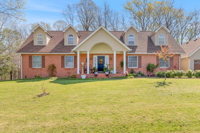 view of front of home with a shingled roof, fence, a front lawn, and brick siding