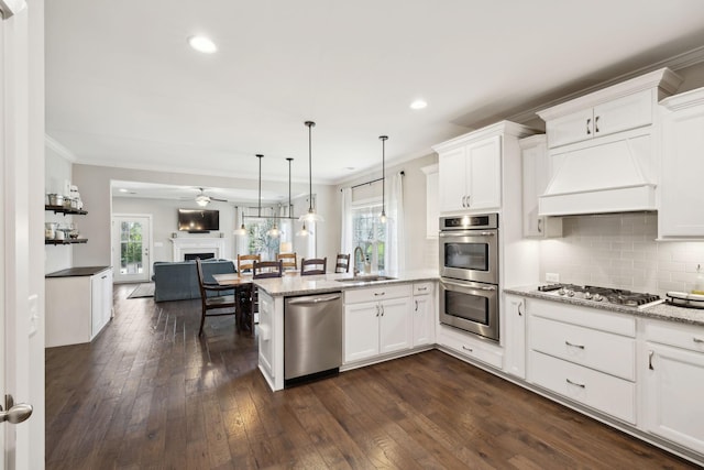 7025 Headwaters Dr, Franklin, TN 37064 - kitchen with crown molding, a peninsula, appliances with stainless steel finishes, a sink, and open floor plan