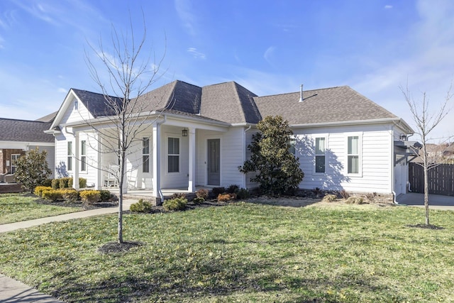 view of front of house with roof with shingles, covered porch, fence, and a front lawn