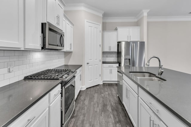 kitchen with tasteful backsplash, white cabinets, appliances with stainless steel finishes, a sink, and dark wood-style floors