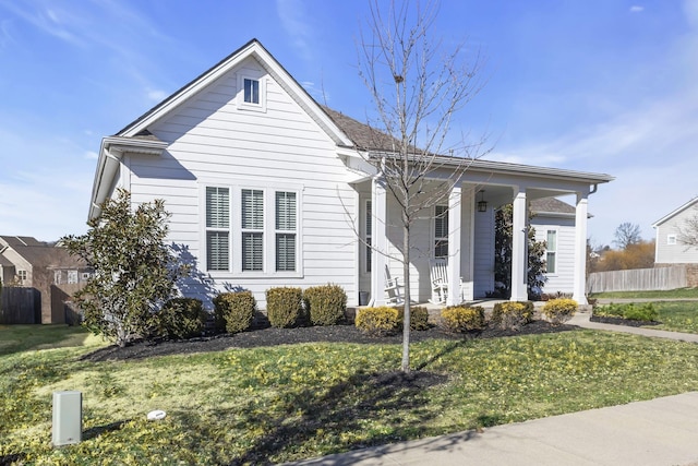 view of front facade with a front yard, fence, and covered porch