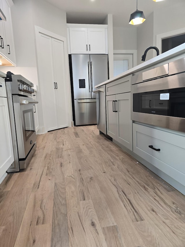 6376B Ivy St, Nashville, TN 37209 - kitchen with hanging light fixtures, white cabinets, ventilation hood, appliances with stainless steel finishes, and light wood-style flooring