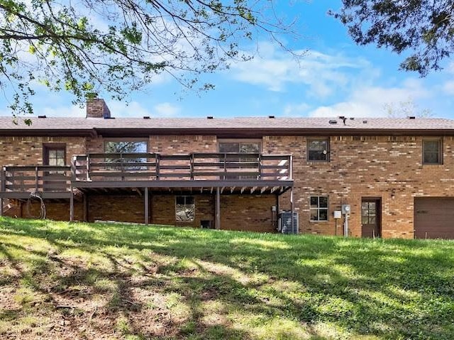 rear view of property with a lawn, a chimney, cooling unit, brick siding, and a wooden deck