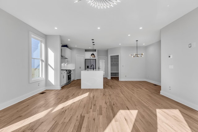 6376D Ivy St, Nashville, TN 37209 - unfurnished living room featuring a notable chandelier, baseboards, visible vents, light wood finished floors, and a sink
