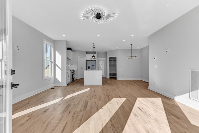 6376D Ivy St, Nashville, TN 37209 - unfurnished living room with light wood-style flooring, an inviting chandelier, baseboards, and recessed lighting