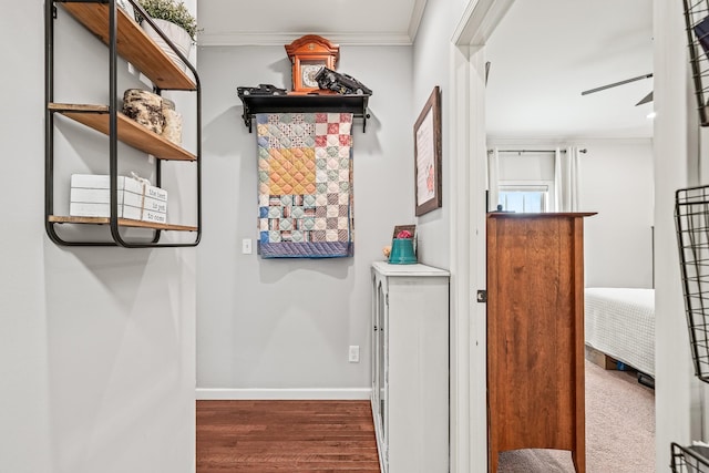 corridor featuring crown molding, wood finished floors, and baseboards