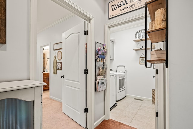 clothes washing area featuring crown molding, visible vents, washing machine and dryer, baseboards, and cabinet space