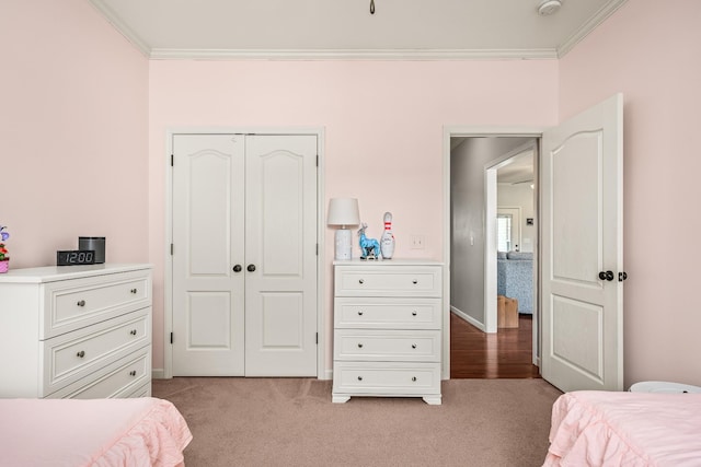 bedroom featuring crown molding, a closet, baseboards, and light colored carpet