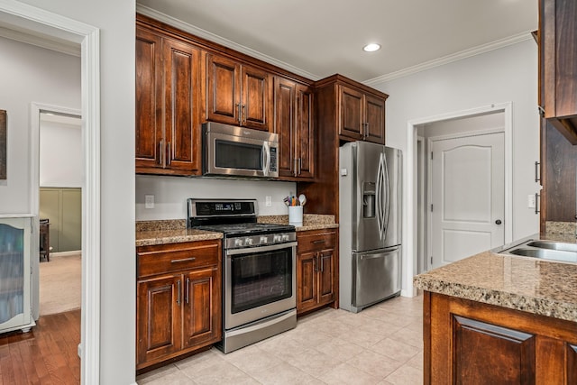 kitchen featuring dark brown cabinetry, ornamental molding, recessed lighting, a sink, and stainless steel appliances