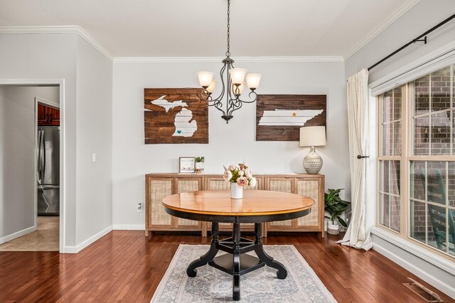 dining room featuring ornamental molding, visible vents, a notable chandelier, and wood finished floors