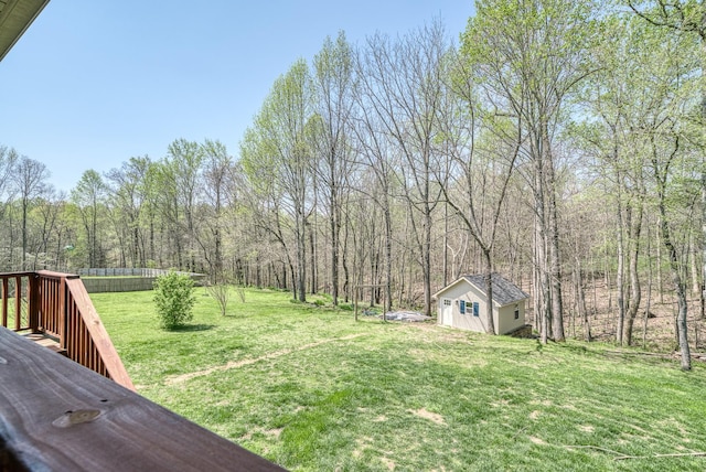 view of yard with a wooded view, fence, and an outdoor structure