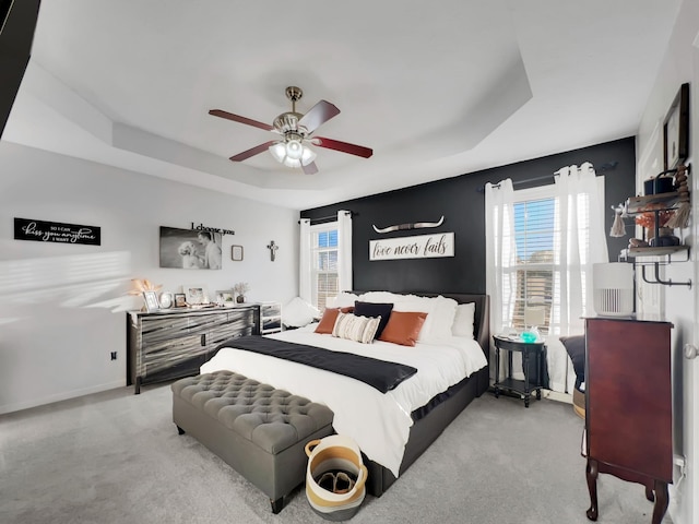 carpeted bedroom with baseboards, a ceiling fan, and a raised ceiling