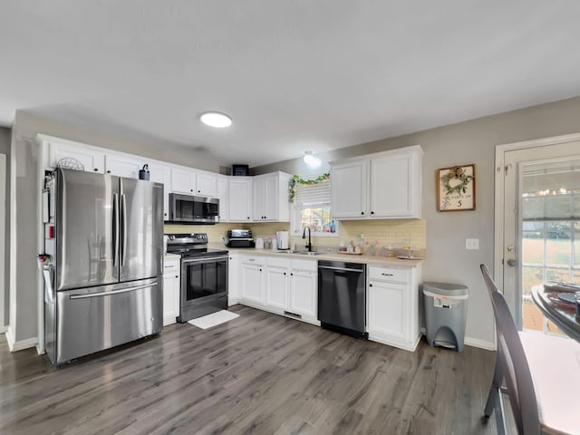 kitchen with light countertops, white cabinets, baseboards, appliances with stainless steel finishes, and dark wood-style floors