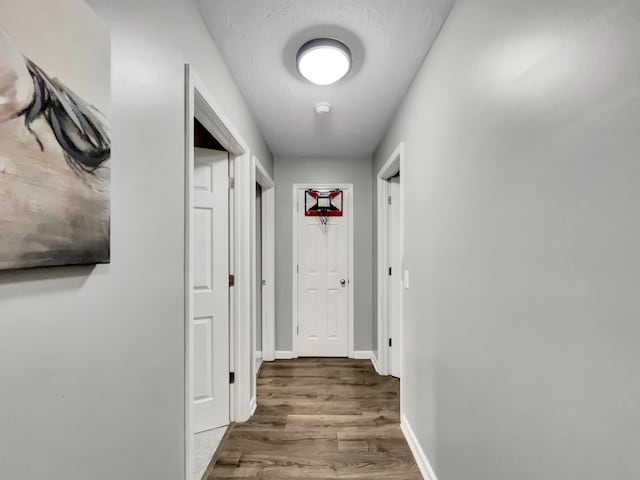 corridor featuring baseboards and wood finished floors
